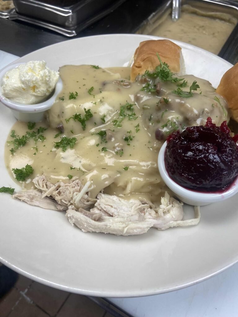 Thanksgiving plate with turkey, mashed potatoes, gravy, rolls, and cranberry sauce.